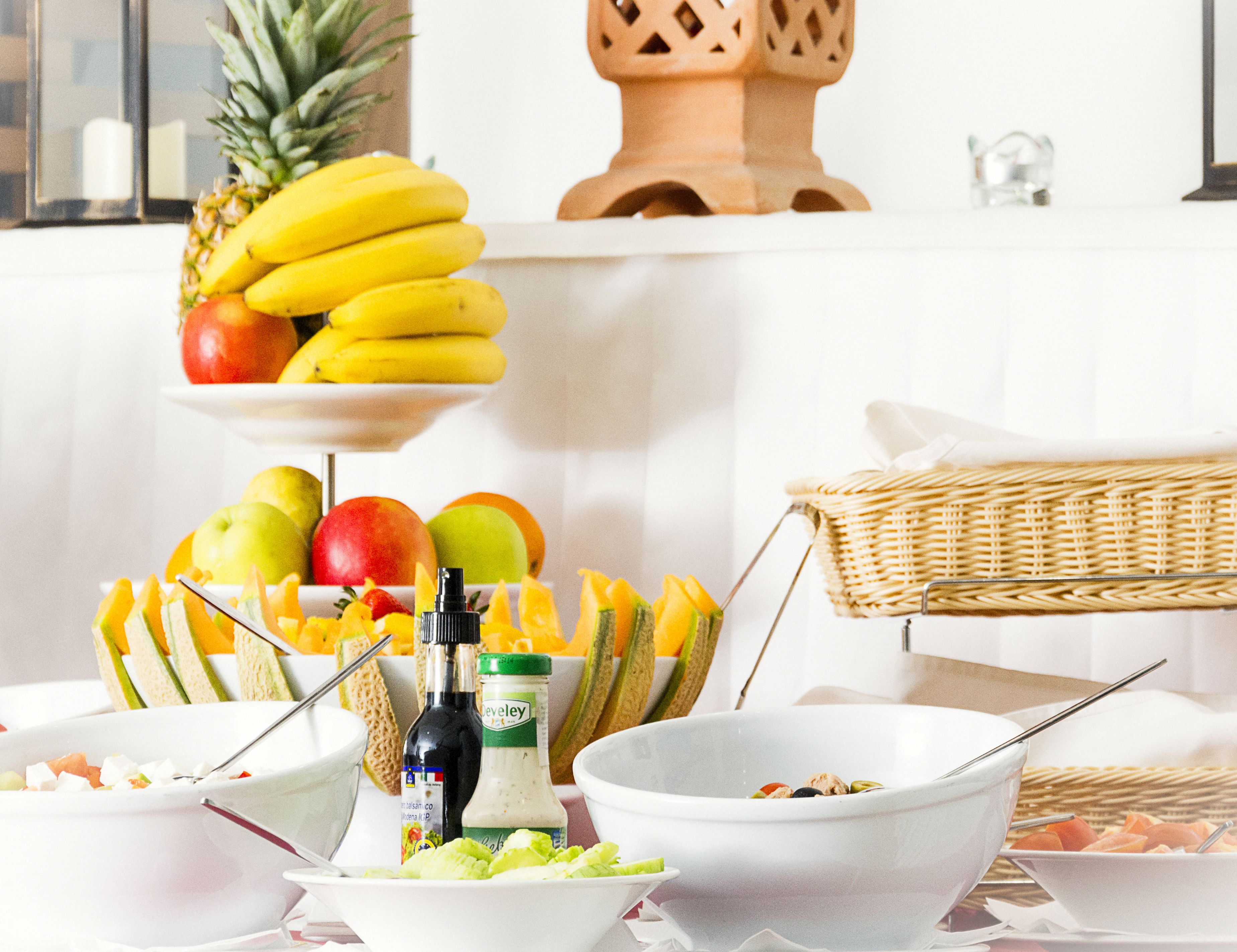 A buffet table with various fruits, salads, and condiments.