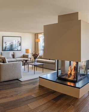 Una sala de estar moderna con chimenea, sofás, una mesa de centro y un cuadro en la pared.