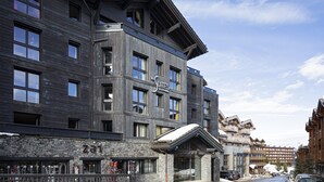 Un hôtel à plusieurs étages doté d’une architecture moderne, caractérisé par de grandes fenêtres et une façade en pierre.