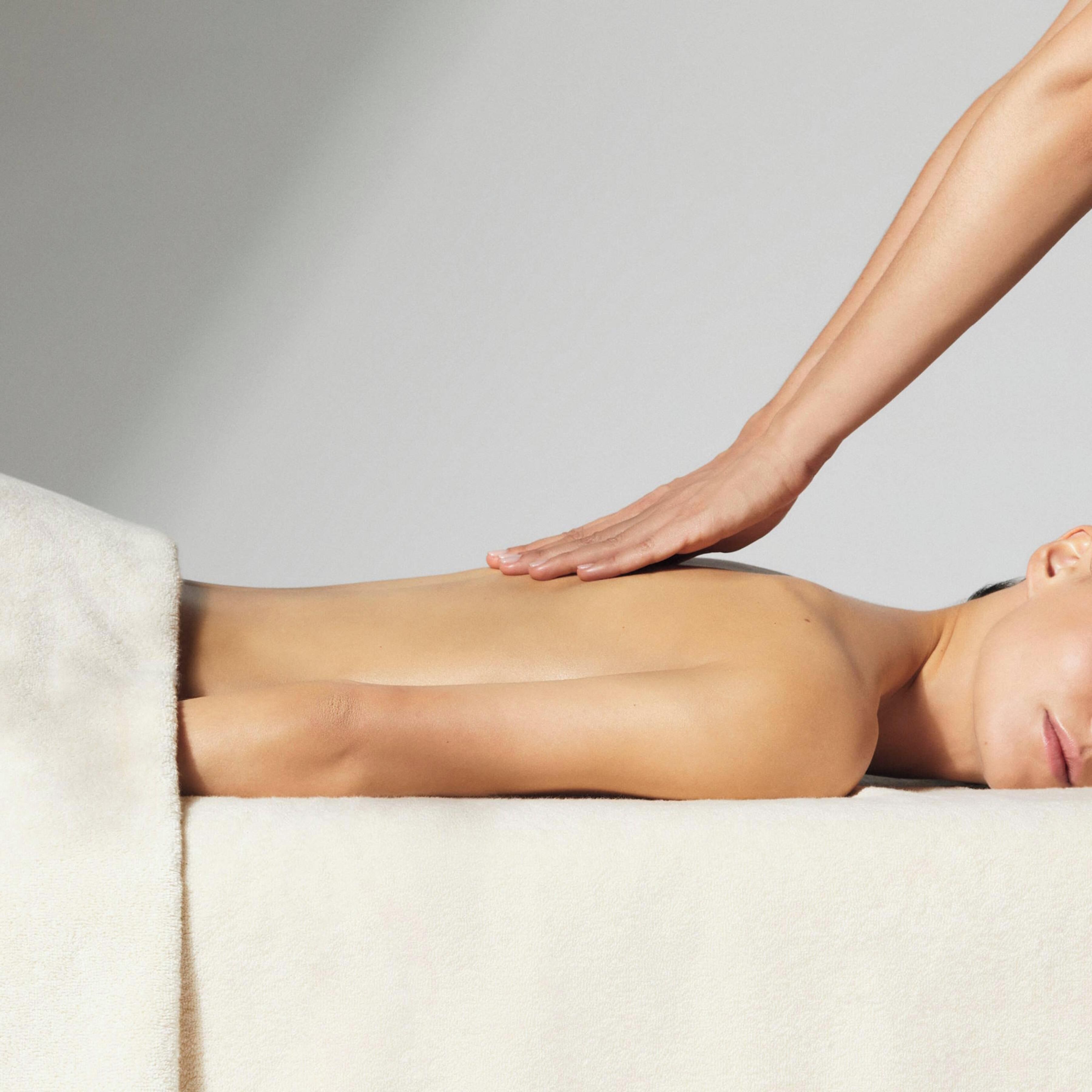 A person receiving a back massage on a massage table.