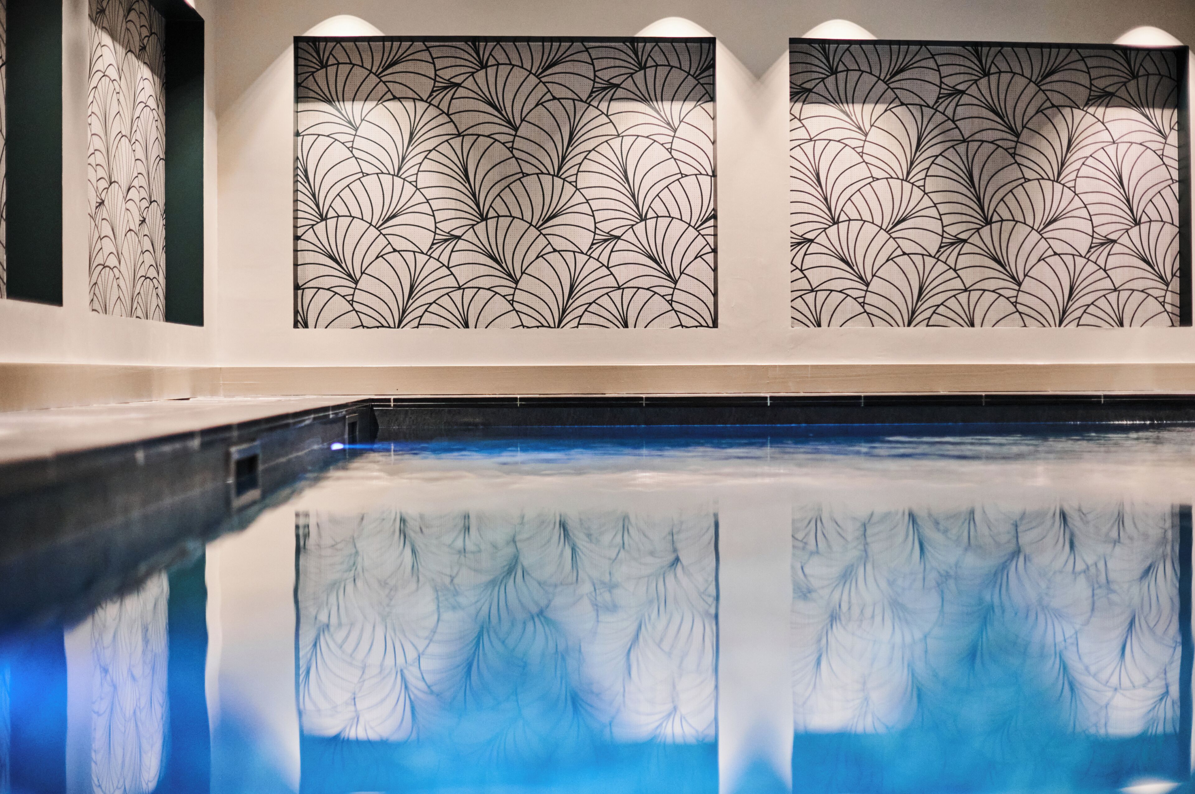 A swimming pool with a reflection of a patterned wall.