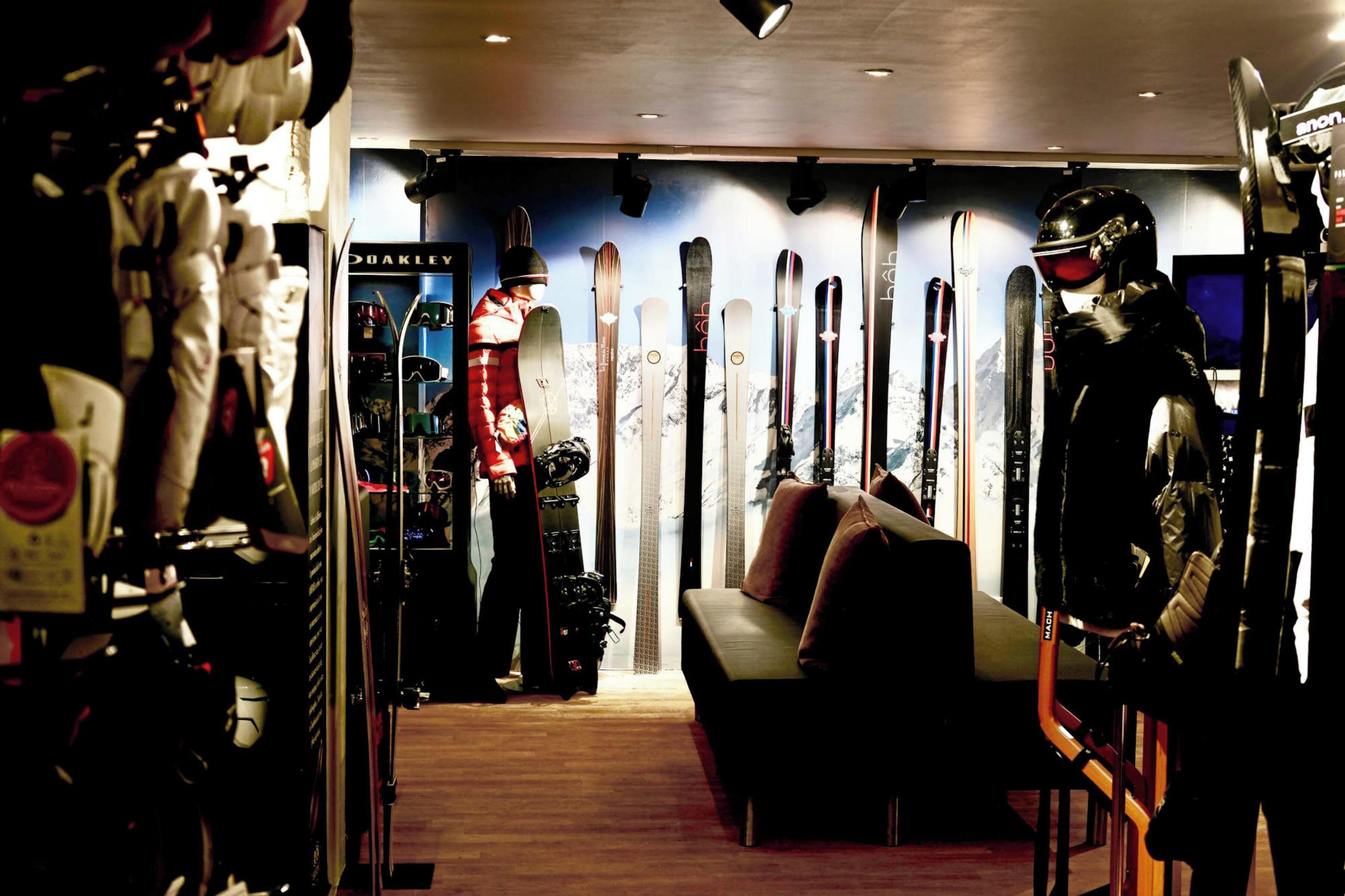 A ski shop with skis and ski gear on display, a couch, and a person in ski gear.