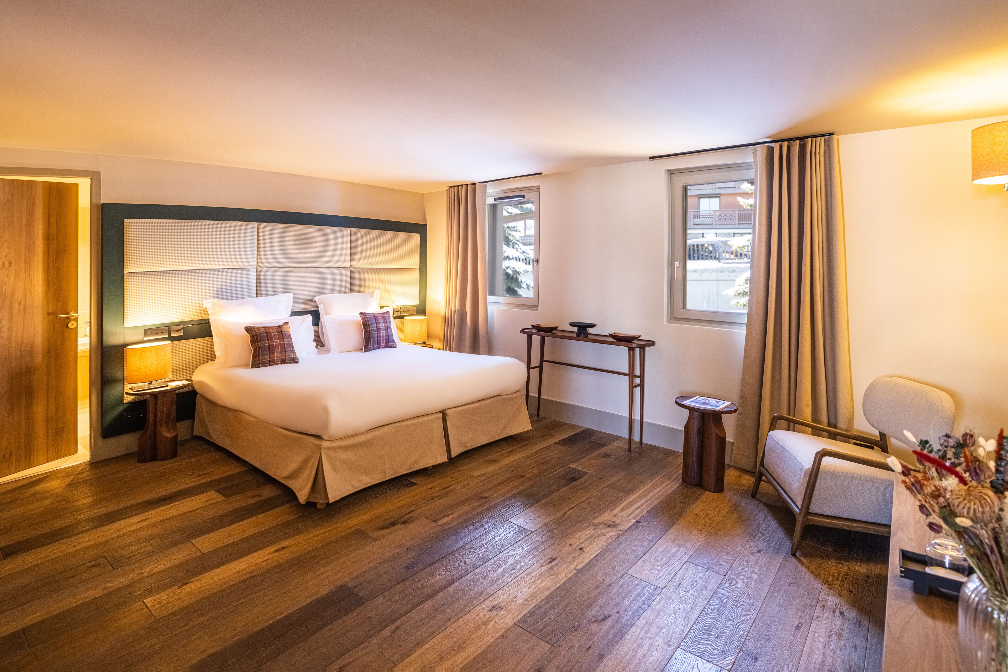 A hotel room with a large bed, bedside tables, a desk, and a chair.