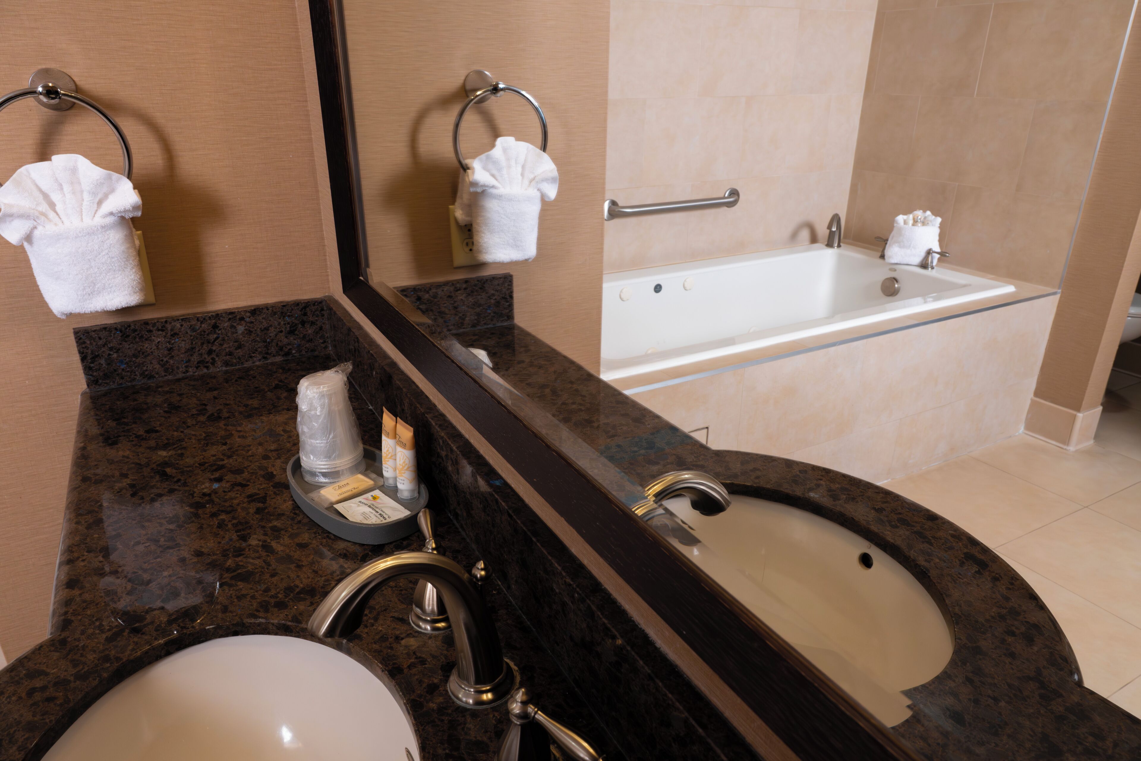A bathroom with a sink, mirror, towel rack, and bathtub.