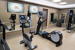 A gym with exercise equipment, mirrors, and a TV displaying WinRiver Resort & Casino. - Win-River Resort & Casino (Redding)