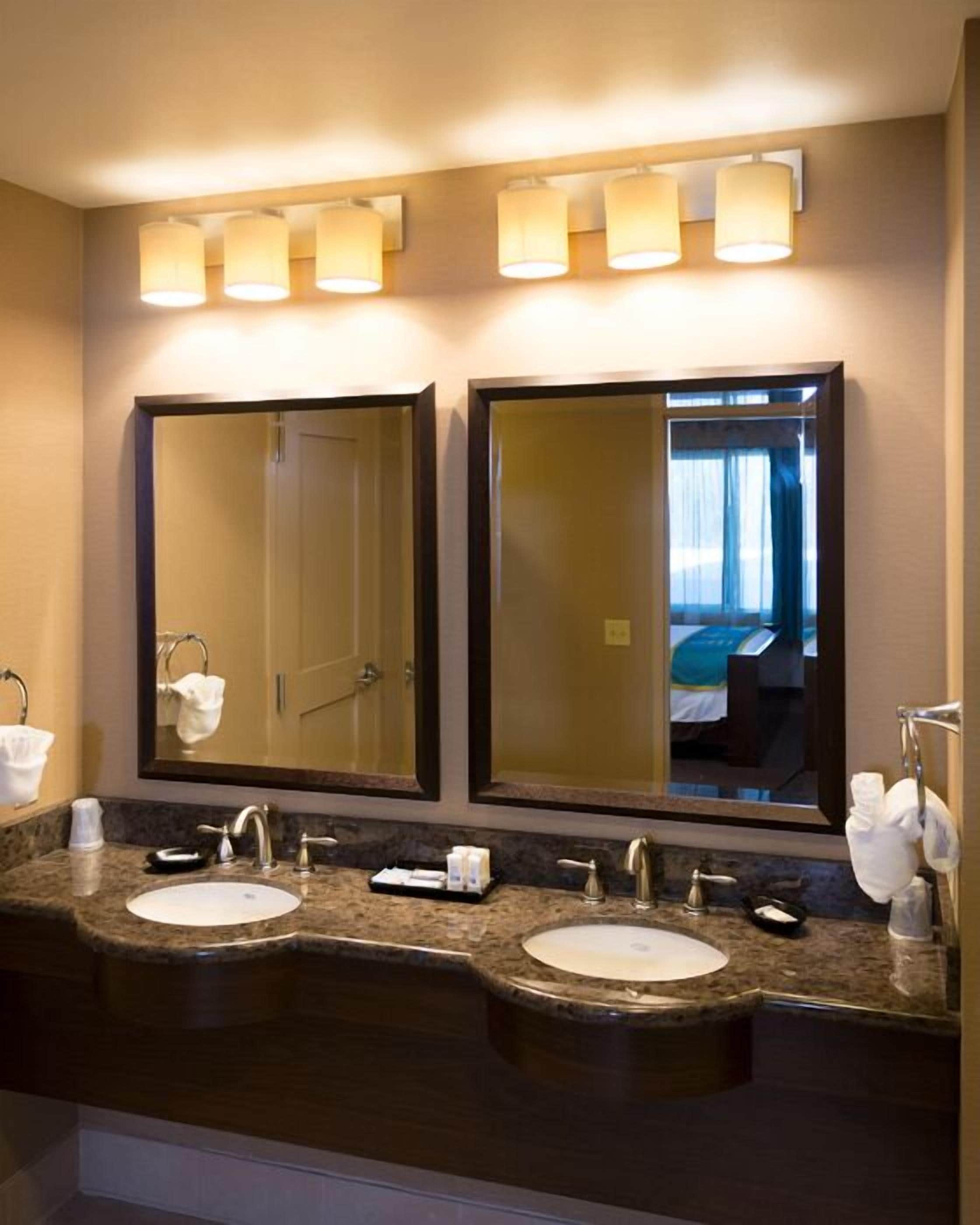 A hotel bathroom with two sinks, a large mirror, and a towel rack.