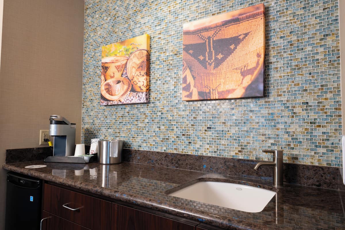 Una cocina con lavamanos, cafetera y azulejos decorativos.