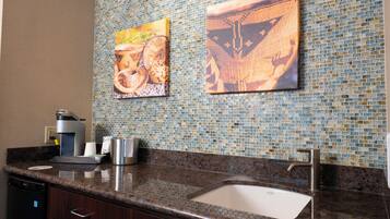 Cozinha com pia, cafeteira e azulejos decorativos.