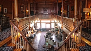 Un hall d’entrée spacieux, agrémenté d’un magnifique escalier, de colonnes en bois et de coins salons confortables.