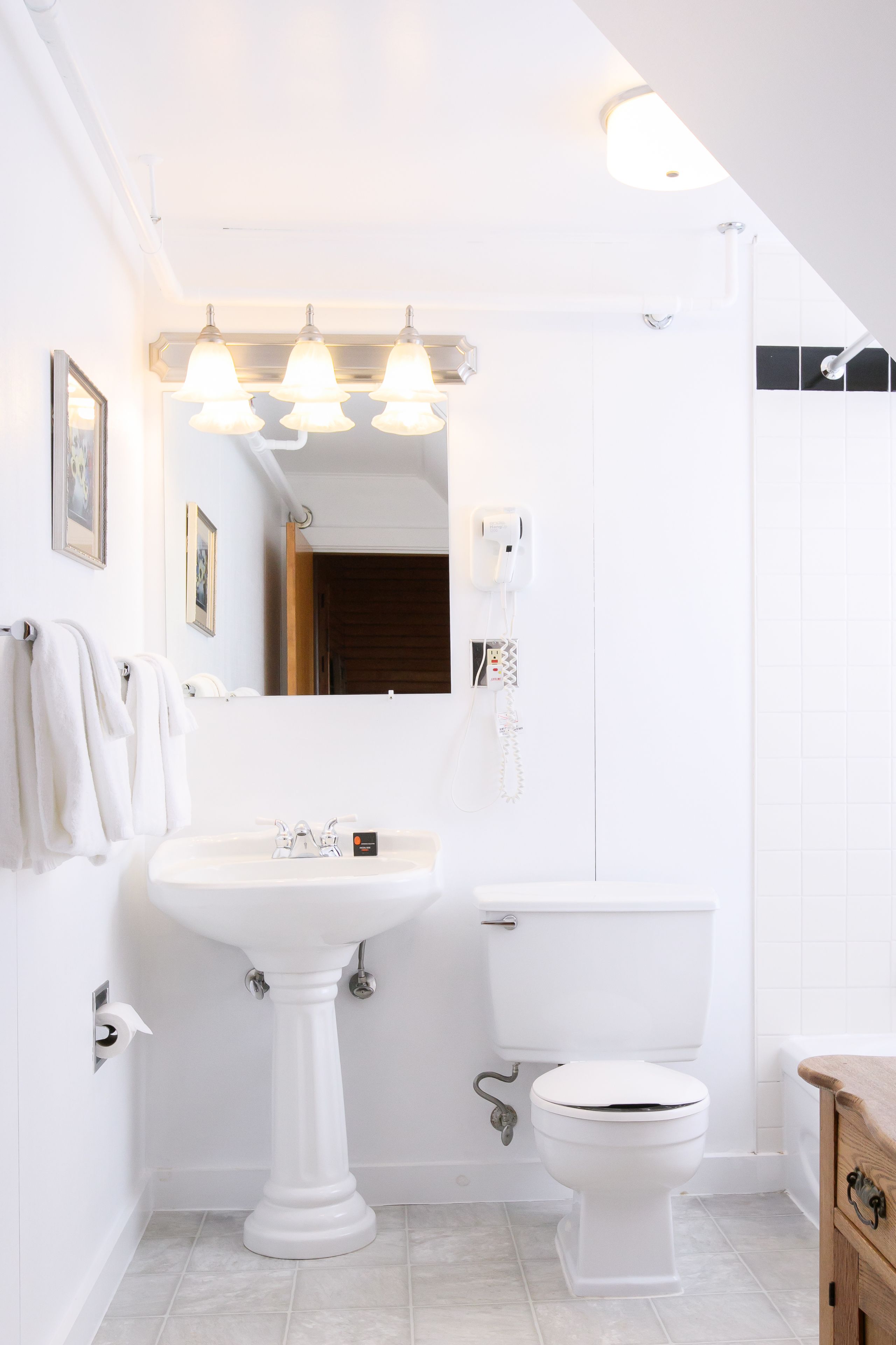 Un baño con lavamanos pedestal, inodoro y tocador.