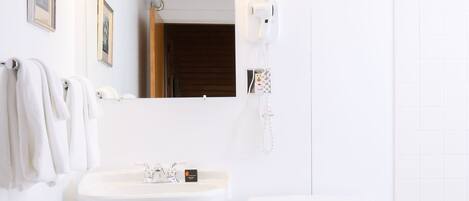Un baño con lavamanos pedestal, inodoro y tocador.