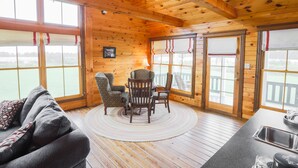L’intérieur d’un chalet en bois comprend un coin repas, un canapé et une cuisine équipée d’un évier.
