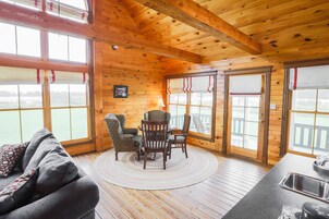 A wooden cabin interior with a dining area, a sofa, and a kitchen with a sink.