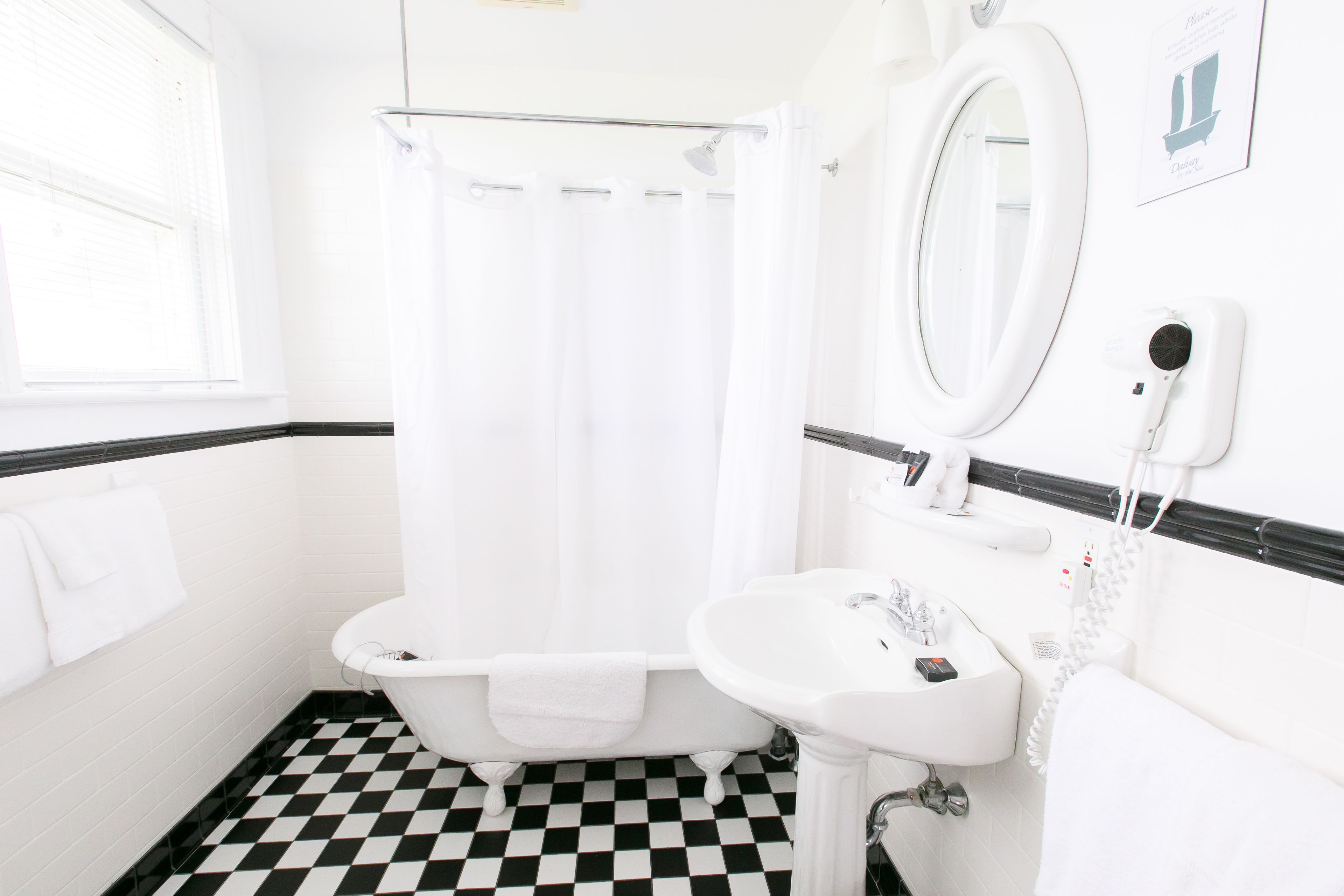 A bathroom with a checkered floor, a bathtub, a sink, and a mirror.