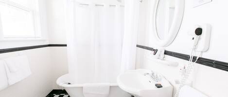 A bathroom with a checkered floor, a bathtub, a sink, and a mirror.