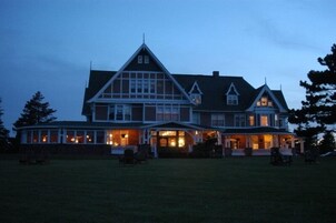 A large, multi-story house with a prominent front porch and multiple windows.