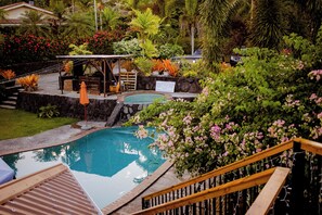 A swimming pool with a wooden deck and a gazebo in a lush garden. - Le Manumea Hotel (Apia)