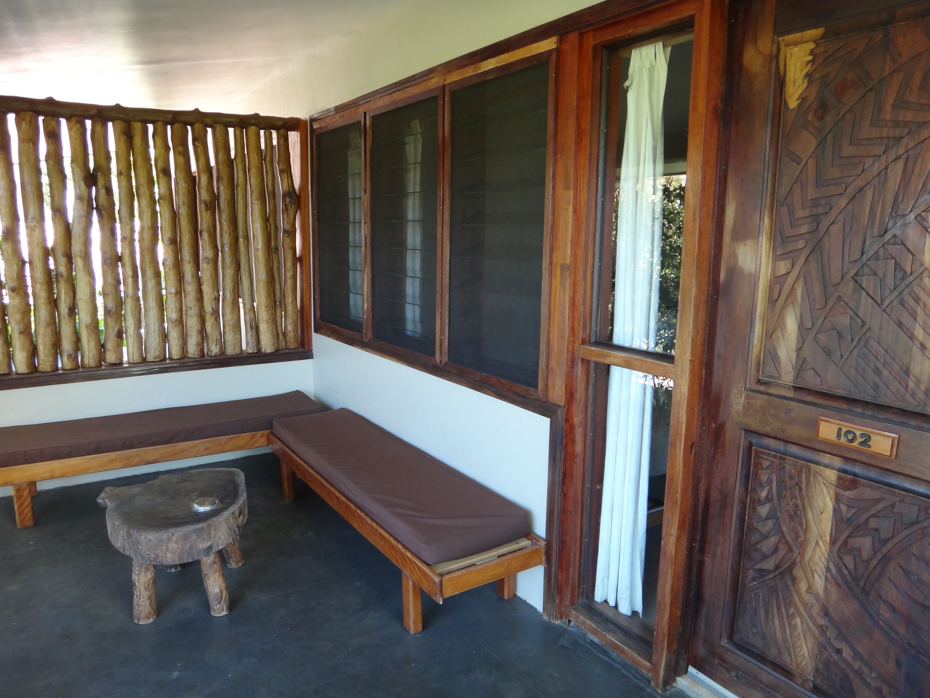A room with a wooden bench, a small stool, and a door with a number plate.