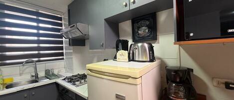 A compact kitchen with a gas stove, a coffee maker, and a microwave.
