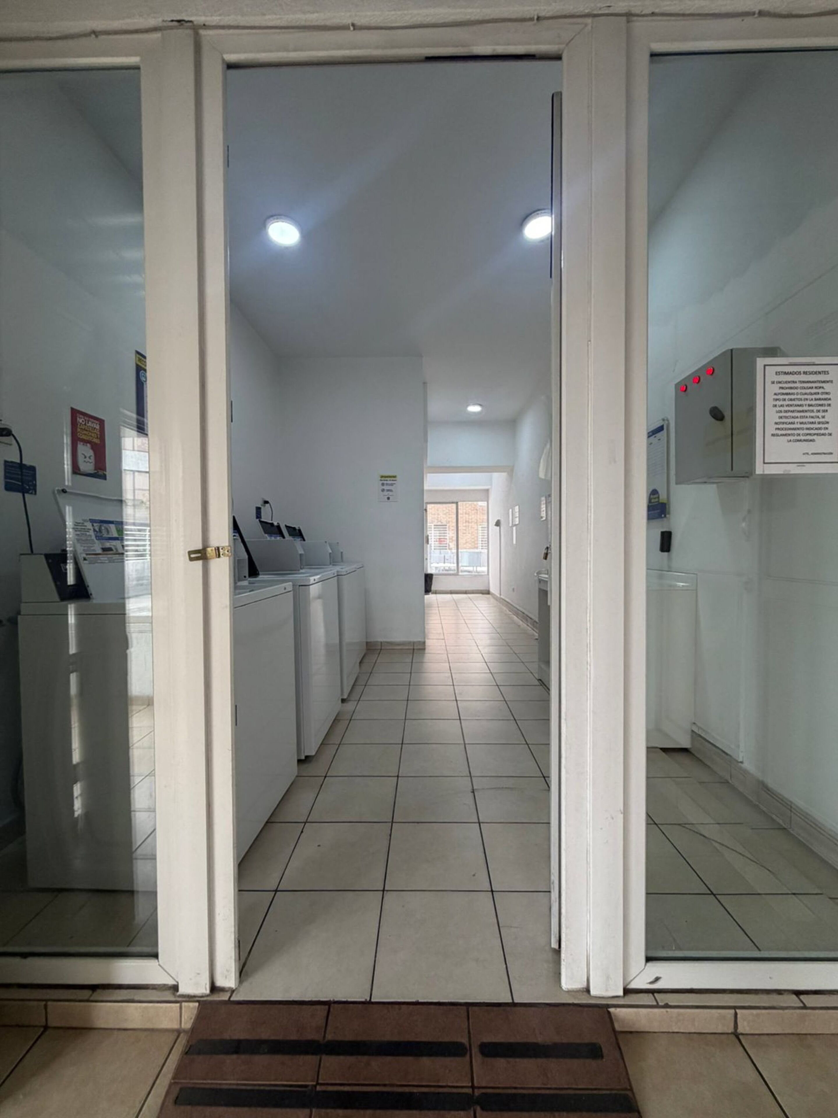 A hallway with a tiled floor, a reception desk, and a door leading to another room.
