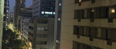 Une rue de la ville au crépuscule, avec des bâtiments modernes, un passage piéton et des lampadaires.
