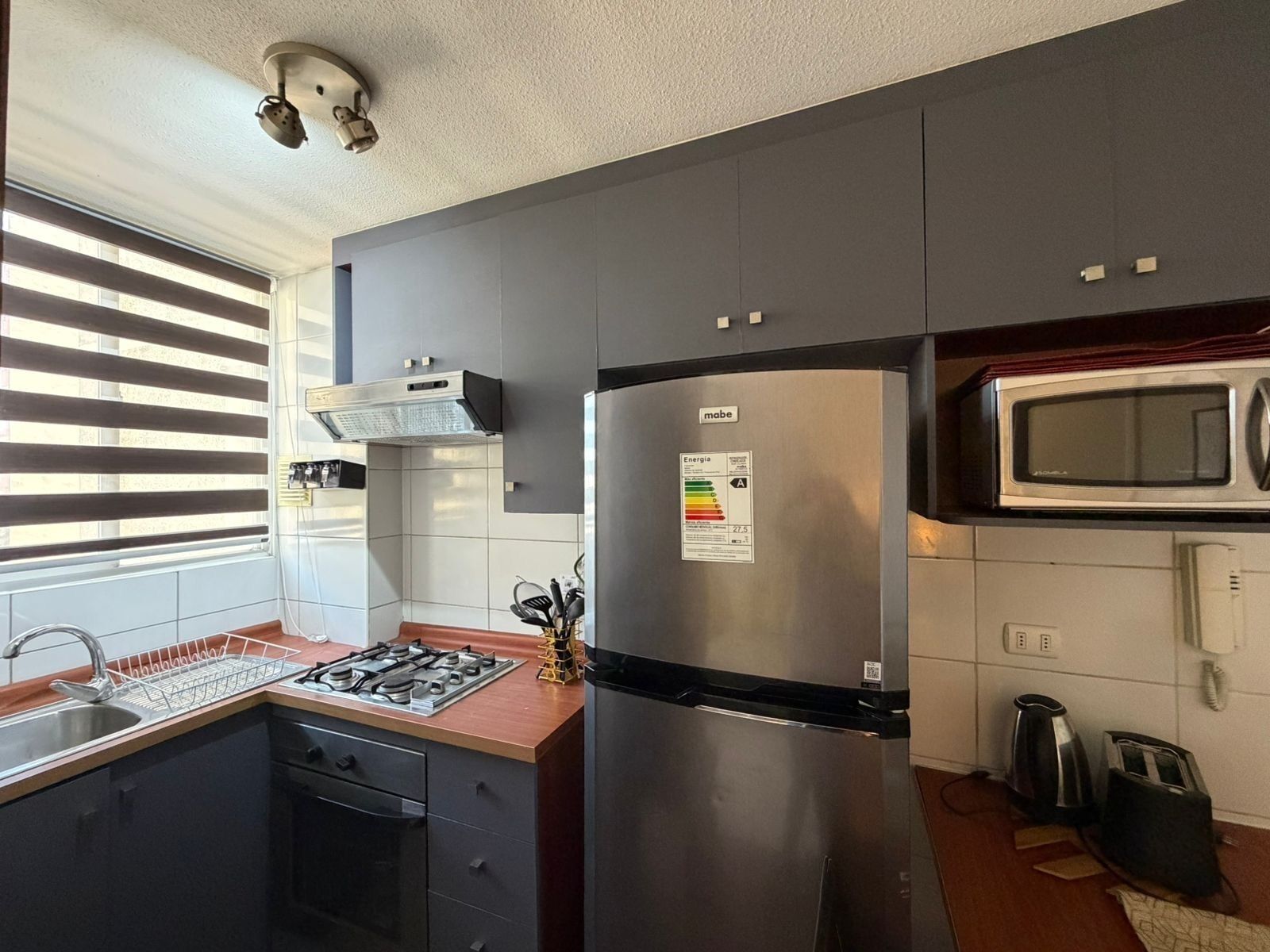 Een moderne keuken met een roestvrijstalen koelkast, een magnetron en een gasfornuis.