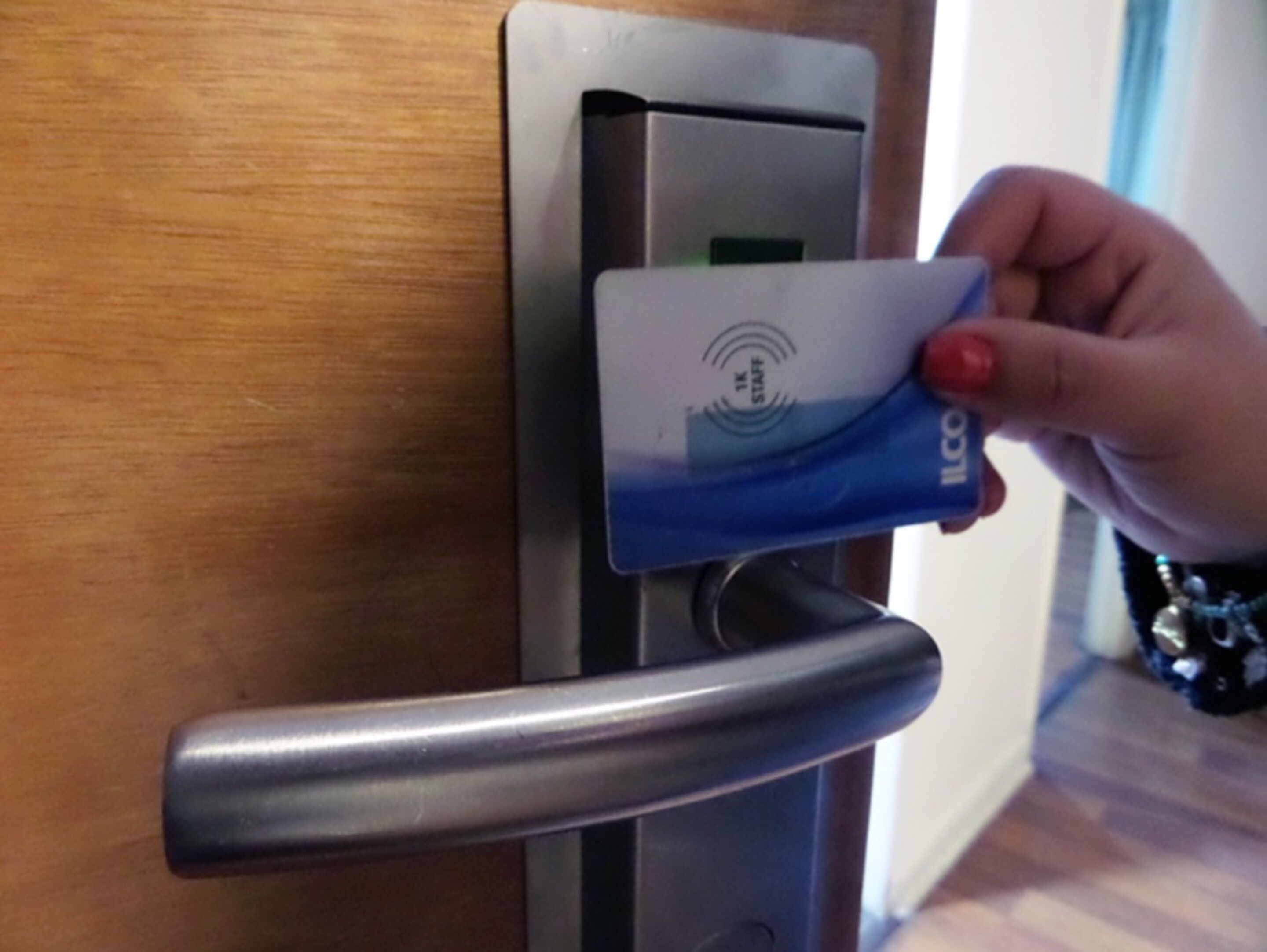 A hand inserting a blue card into a card reader on a door.
