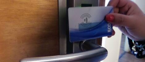 A hand inserting a blue card into a card reader on a door.