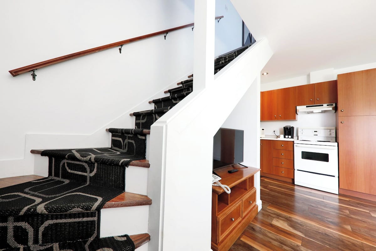 A modern kitchen with wooden cabinets, a built-in oven, and a countertop with a coffee maker.