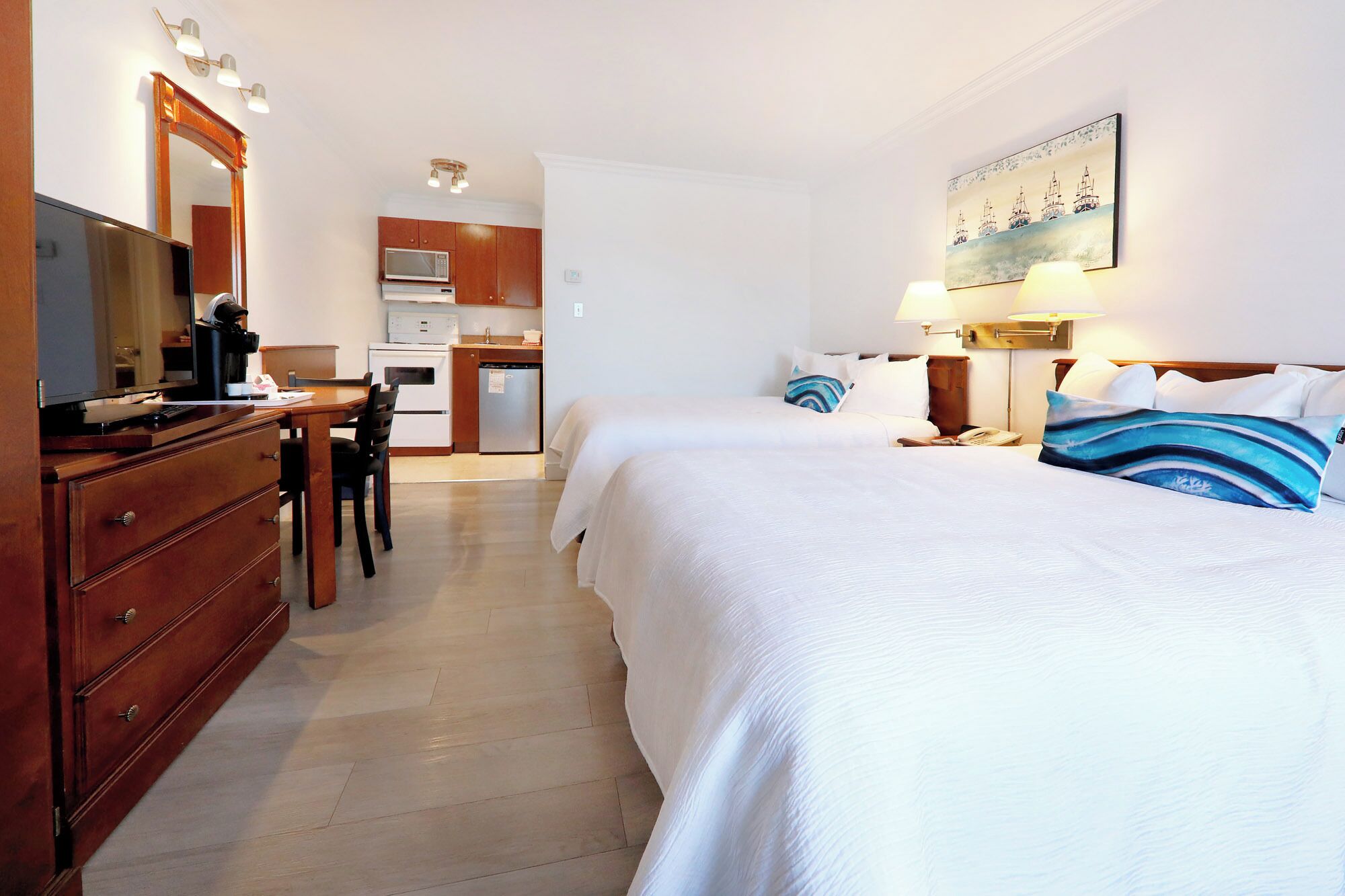 Una habitación de hotel con cama, escritorio, computadora, microondas y refrigerador.