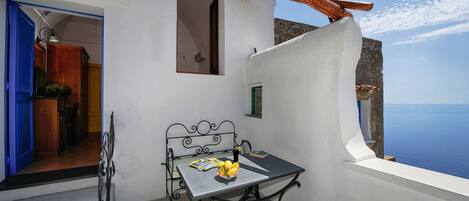 Uma varanda com uma mesa, uma cadeira e vista para o mar.