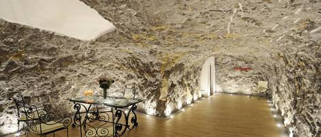 Ein Essbereich mit rustikaler Steinwand, Holzboden und Metallstühlen an einem Glastisch.