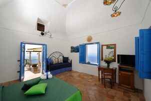Un dormitorio con cama, escritorio, televisor y vista al mar a través de una ventana.