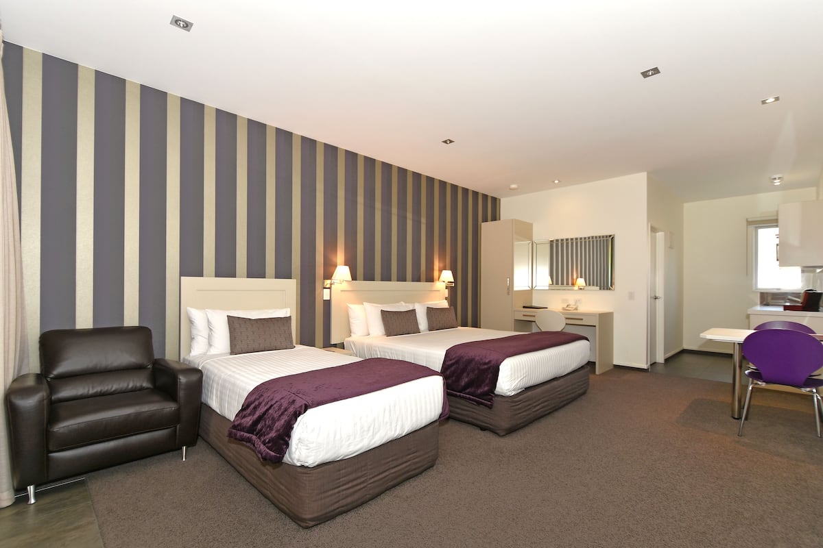 Ein Hotelzimmer mit zwei Betten, einem Schreibtisch, einem Stuhl und einem Badezimmer.