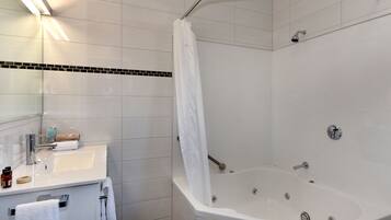Un baño moderno con lavamanos, espejo y bañera blancos.