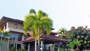 Un edificio tradicional con tejado de baldosas, un corredor cubierto y un jardín cuidado con diversas plantas.