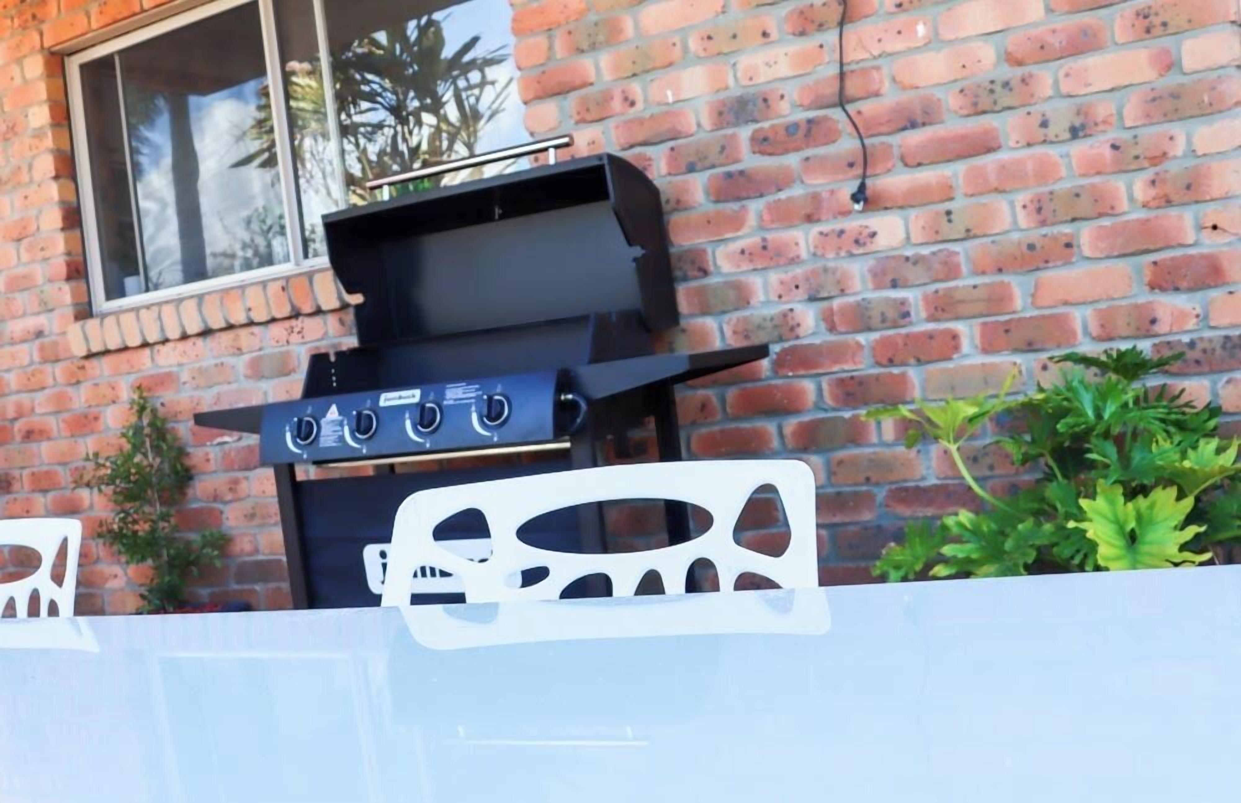 A barbecue grill against a brick wall.