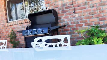 A barbecue grill against a brick wall.