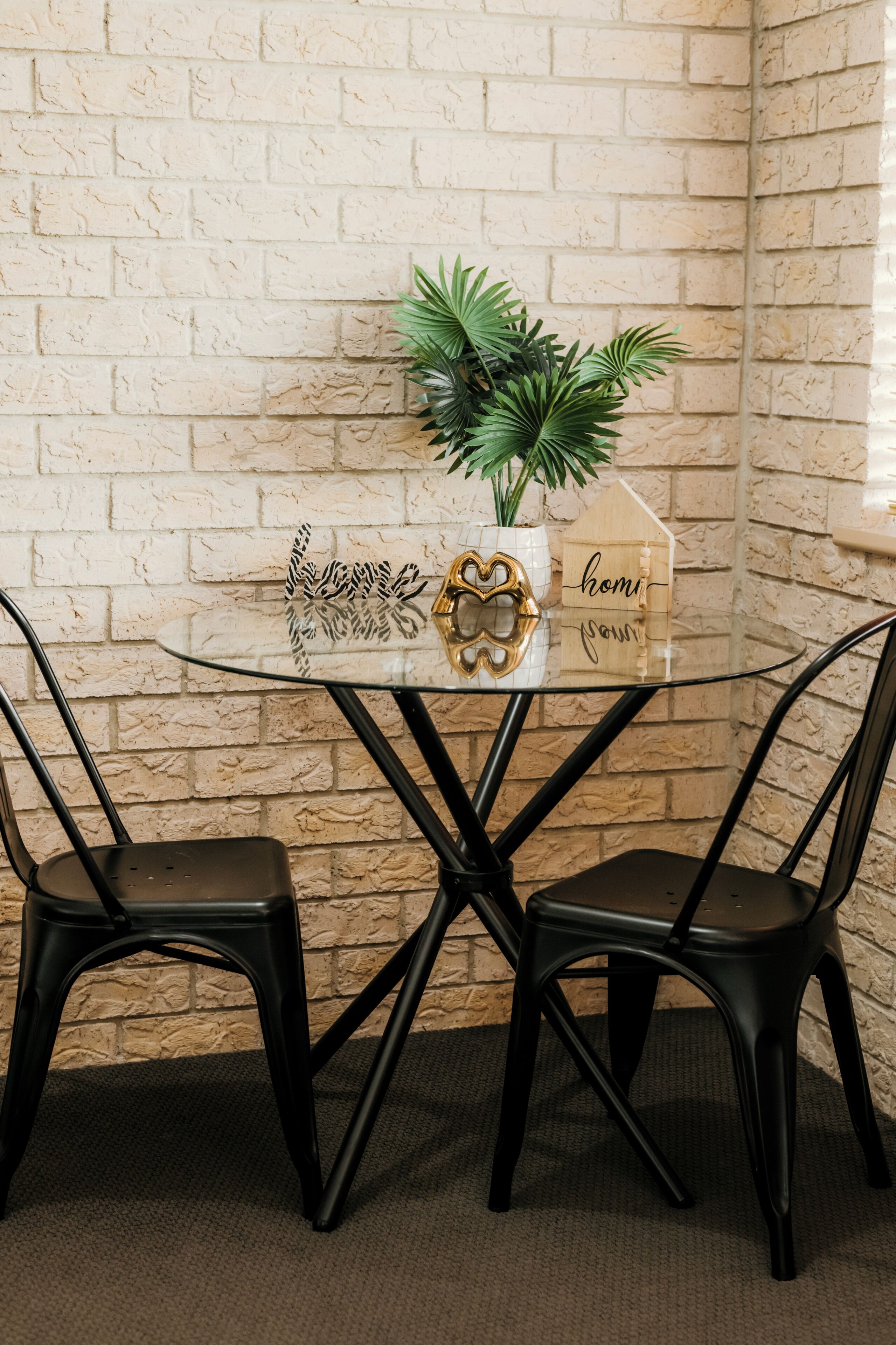 A glass-top table with a plant and a sign that reads 'home sweet home.'