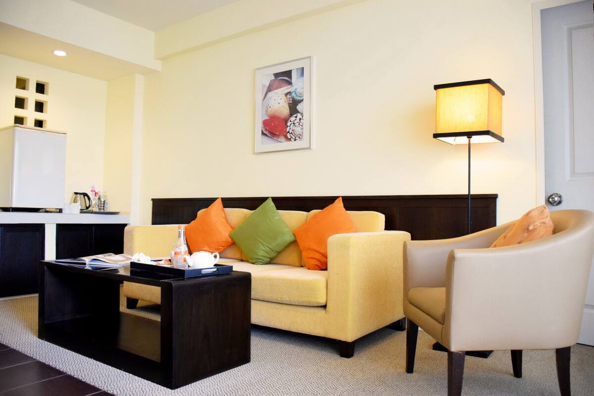 A living room with a sofa, armchair, coffee table, and a lamp.