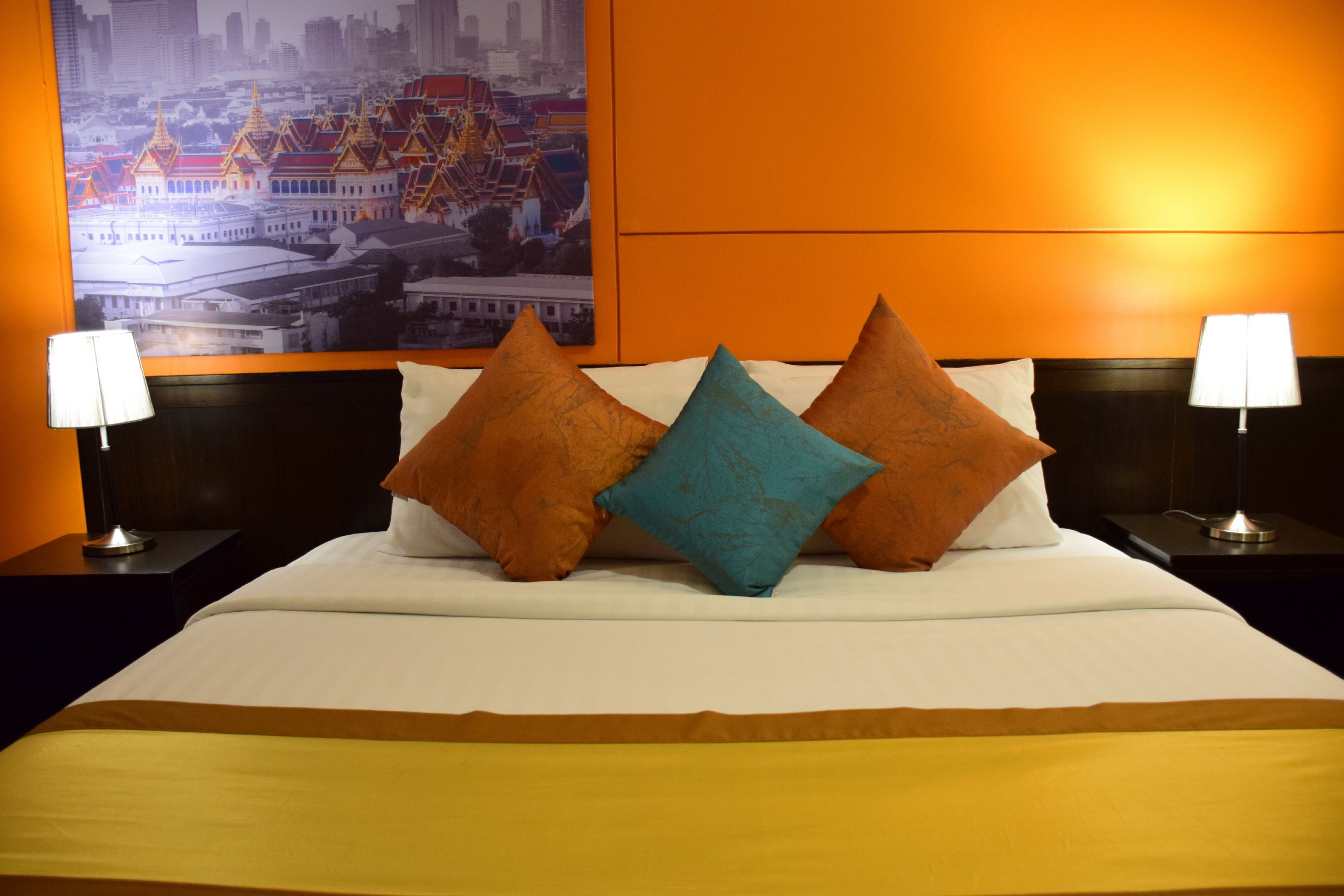 A hotel room with a large bed, two nightstands with lamps, and a cityscape poster on the wall.
