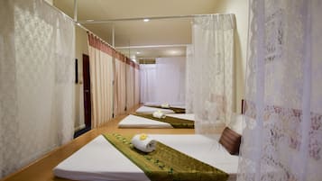 Cozy beds line a central walkway in this inviting room, each with a neatly folded mattress and decorative runner.