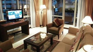 Een moderne woonkamer met een televisie, bank, fauteuil en salontafel.