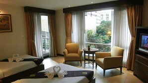 Een hotelkamer met twee bedden, een televisie, een tafeltje en een stoel.