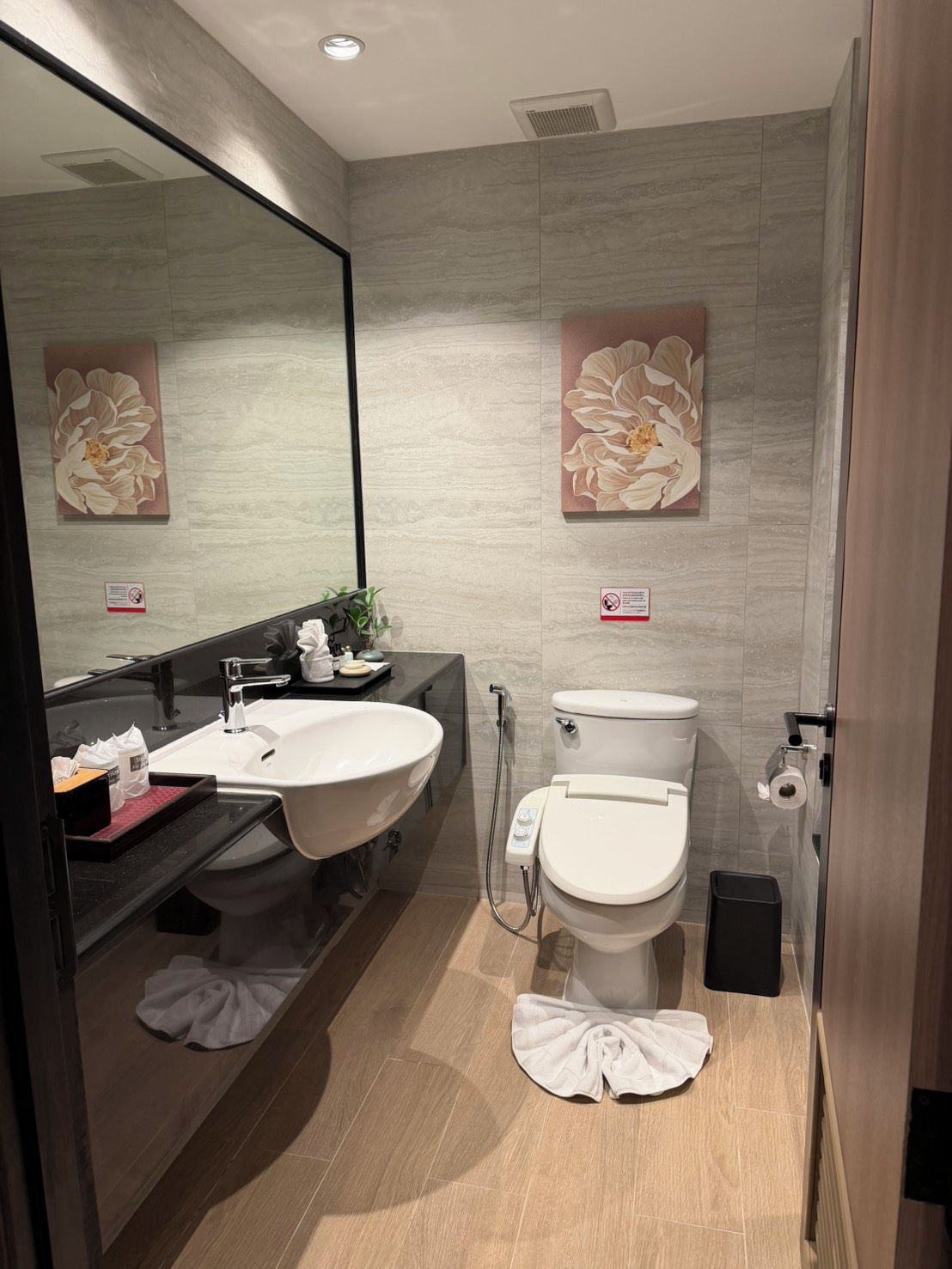 A modern bathroom with a large mirror, a sink, a toilet, and a shower.