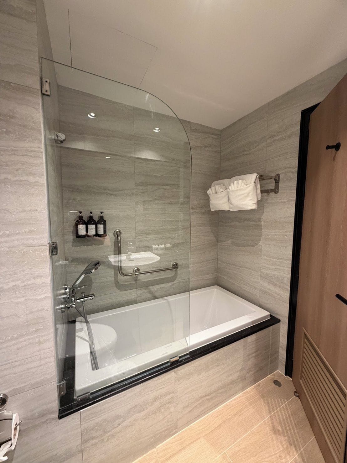 A modern bathroom with a glass-enclosed shower, a standalone bathtub, and a towel rack.