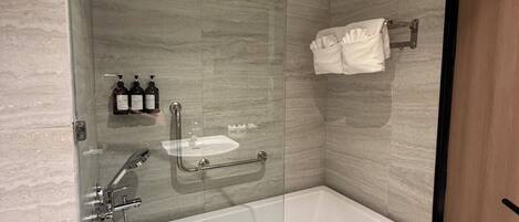 A modern bathroom with a glass-enclosed shower, a standalone bathtub, and a towel rack.