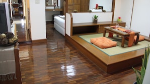 Ein traditioneller japanischer Raum mit Tatami-Boden, einem niedrigen Holztisch mit Kissen und einem Schiebetürenschrank.