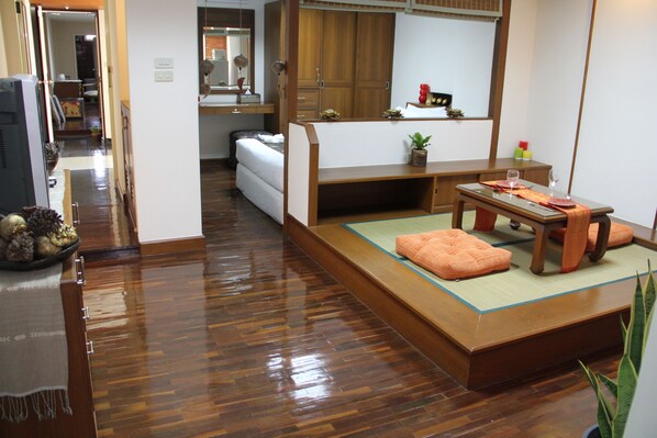 Um quarto tradicional japonês, com tatames, uma mesa de madeira baixa com almofadas e um guarda-roupa com portas deslizantes.