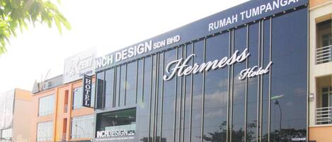 Un hotel con un cartel grande que indica "Hermes Hotel" y "Inch Design SDN BHD" en la fachada.